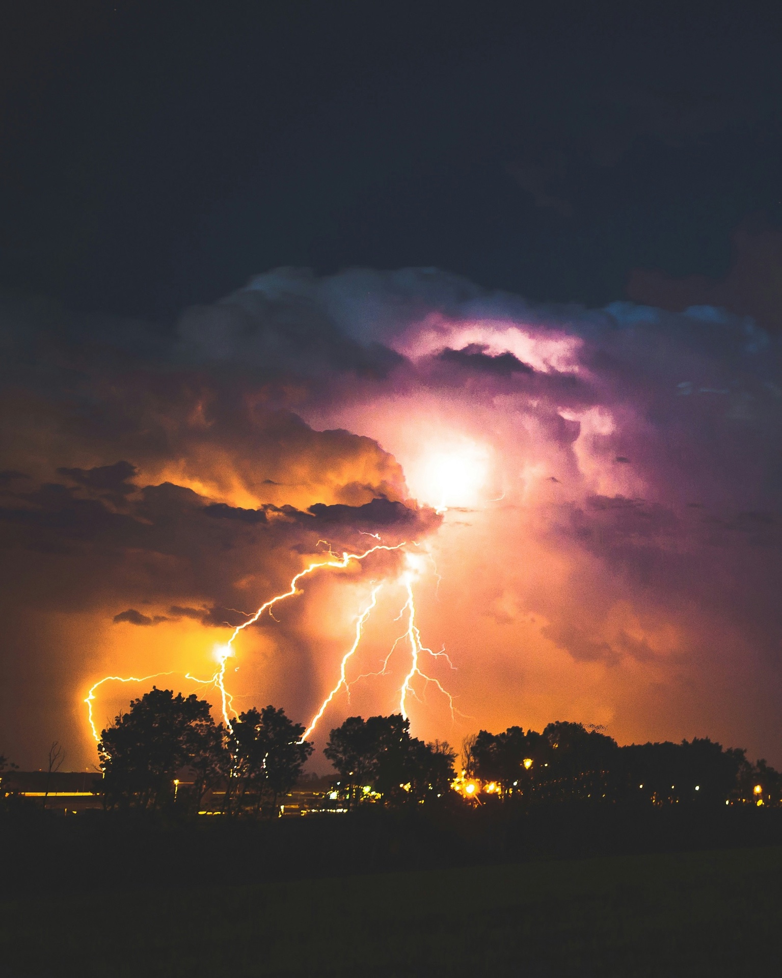 Lightning striking over a residential neighborhood at dusk